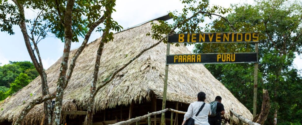 Emberá community greeting visitors beside river huts